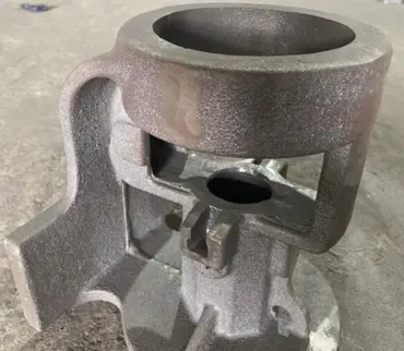 A piece of industrial-use metal casting equipment with a big hole in the center on the production facility's floor.
