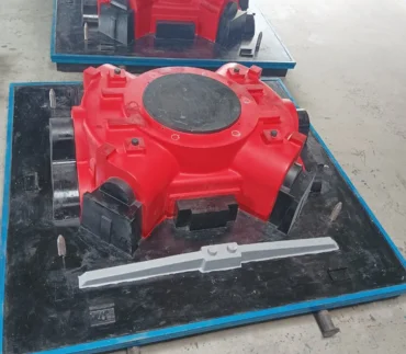 A red and black McLanahan mechanical device on the floor of a manufacturing facility that makes patterns and castings