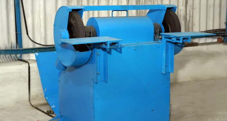 A blue mechanical device with two wheels on either side and a place to hold the product in a manufacturing unit.