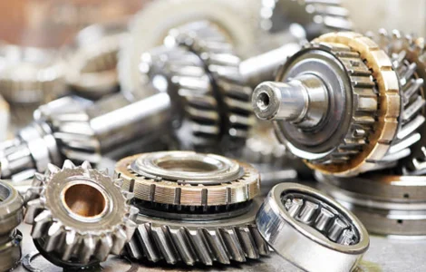 A stack of gears, some scattered and dismantled and some assembled, lies on the table in a manufacturing unit.