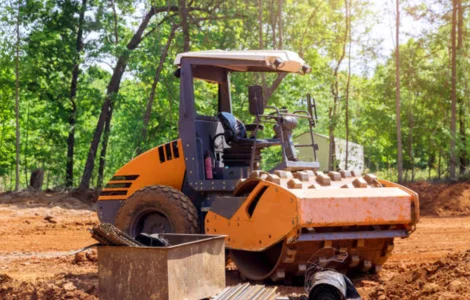 Best Spare Parts Providers For Earthmoving Equipment A robust construction machine actively engaged in road maintenance on a dirt path, with dedication & professionalism.