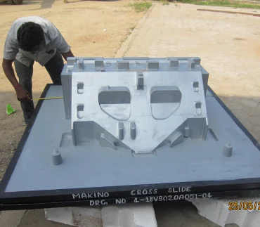 A worker measuring the finished makind cross slide equipment on the floor for inspection, ensuring quality and standard