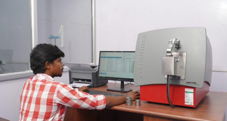 A man sitting at a workstation, seated at desk, engaged in computer-related tasks related to cast & SG ductile iron.