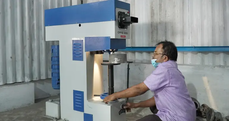 A male worker uses a specialized instrument to precisely fabricate a metal component in a manufacturing unit.